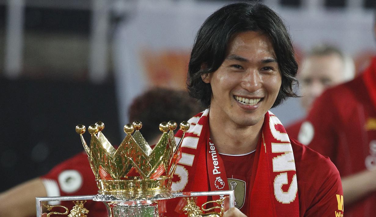 Selebrasi gelandang Liverpool, Takumi Minamino dengan trofi juara Liga Inggris 2019/2020 setelah laga menghadapi Chelsea di Anfield Stadium, Liverpool (22/7/2020). Takumi Minamino menjuarai Liga Inggris bersama Liverpool pada musim 2019/2020. Takumi Minamino diboyong langsung Liverpool dari RB Salzburg pada tengah musim 2019/2020. Pada awal musim 2022/2023 Liverpool melepasnya ke AS Monaco setelah sempat dipinjamkan ke Southampton. (AFP/Pool/Phil Noble)