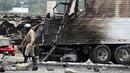 Petugas keamanan setempat memeriksa bangkai truk yang telah hangus usai terjadi tabrakan antara dua truk besar di utara pusat kota Los Angeles (25/4). (AP Photo/Reed Saxon)