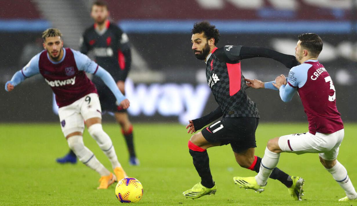 Penyerang Liverpool, Mohamed Salah, berebut bola dengan pemain West Ham United, Aaron Cresswell, pada laga Liga Inggris di Stadion London, Minggu (31/1/2021). Liverpool menang dengan skor 3-1. (Clive Rose/Pool via AP)