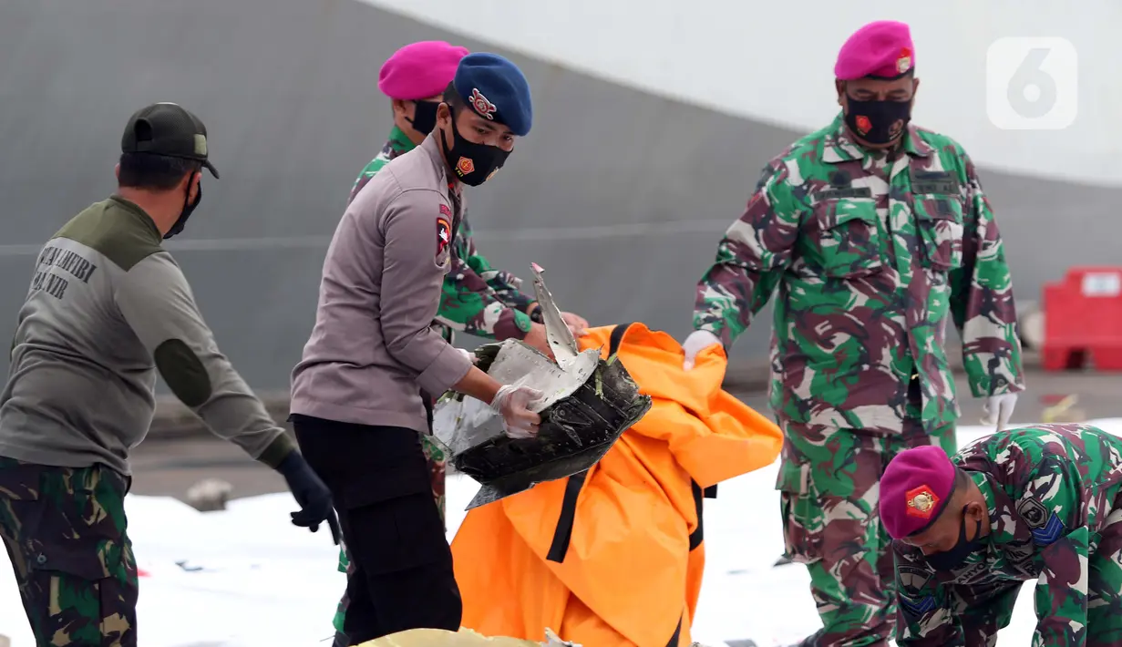 Polisi dan tentara mengumpulkan serpihan pesawat Sriwijaya Air SJ 182 di Dermaga JICT 2, Jakarta, Minggu (10/1/2021). Tim selam Marinir TNI AL menemukan dan mengevakuasi serpihan Sriwijaya Air SJ 182 yang kemudian diserahkan ke Basarnas, Kepolisian, serta KNKT. (Liputan6.com/Helmi Fithriansyah)