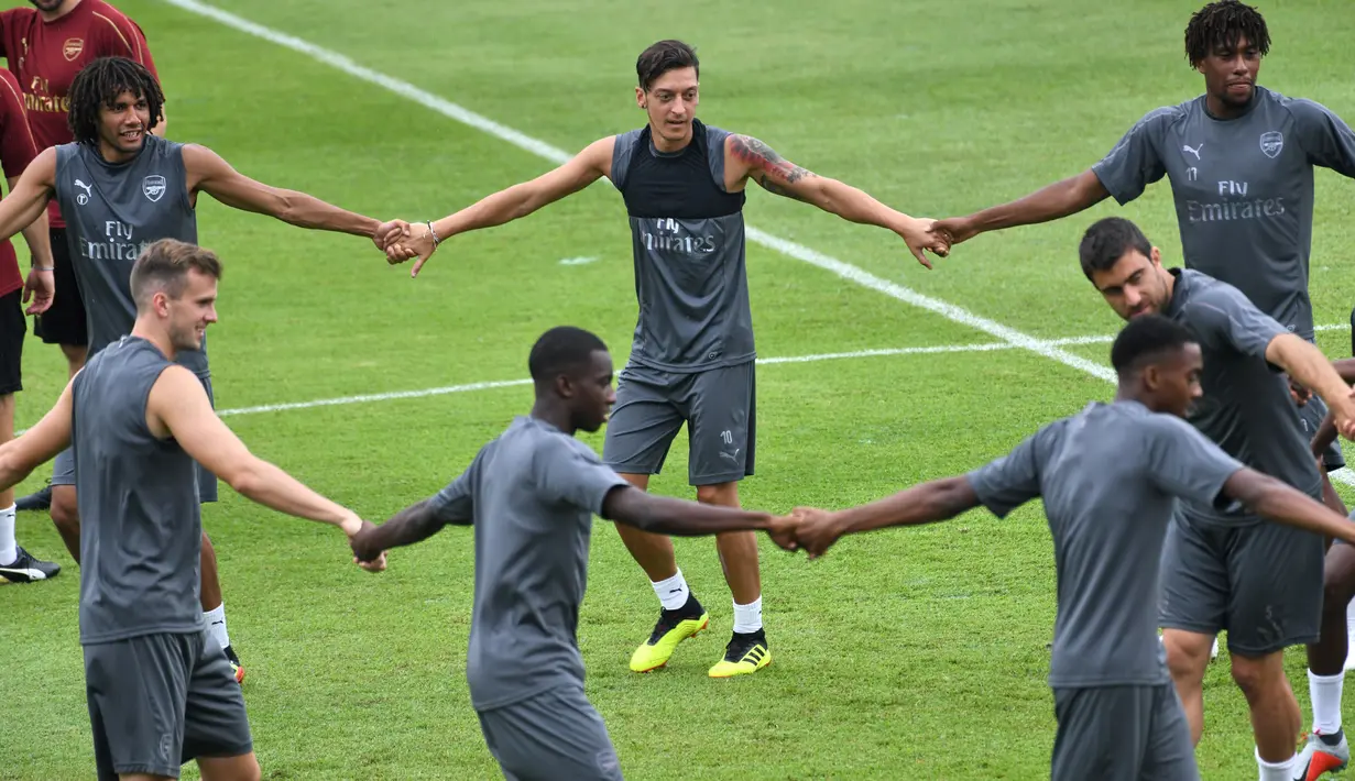 Gelandang Arsenal, Mesut Ozil (tengah) menjalani sesi latihan untuk kompetisi pramusim International Champions Cup (ICC) 2018 di Singapura, Rabu (27/5). Menjelang duel kontra Atletico Madrid, Ozil dkk menikmati sesi latihan ringan. (AFP/Roslan RAHMAN)