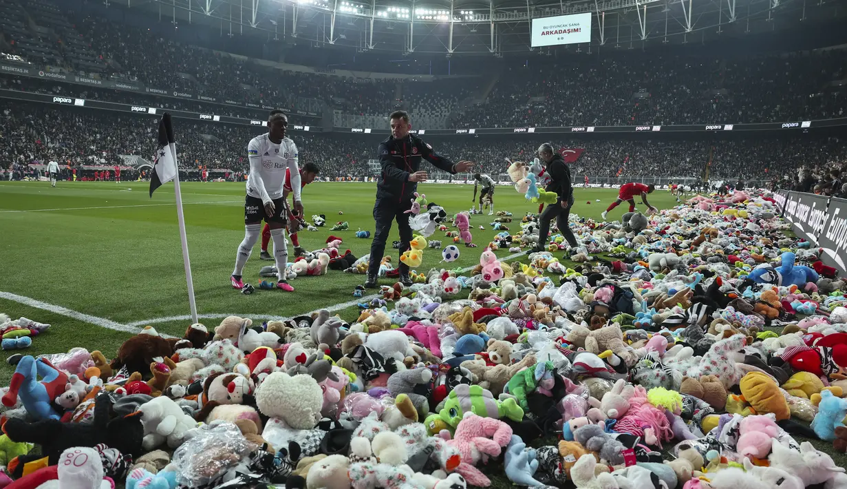 Suporter melempar mainan ke lapangan selama pertandingan Liga Turki (Super Lig) antara Besiktas dan Antalyaspor di stadion Vodafone di Istanbul, Minggu (26/2/2023). Setelah gempa dahsyat Turki, pusat kekuatan sepak bola Istanbul memulai kampanye yang mengharukan dengan meminta para penggemar untuk membawa mainan boneka ke kandang Vodafone Park Besiktas.  (AP Photo)
