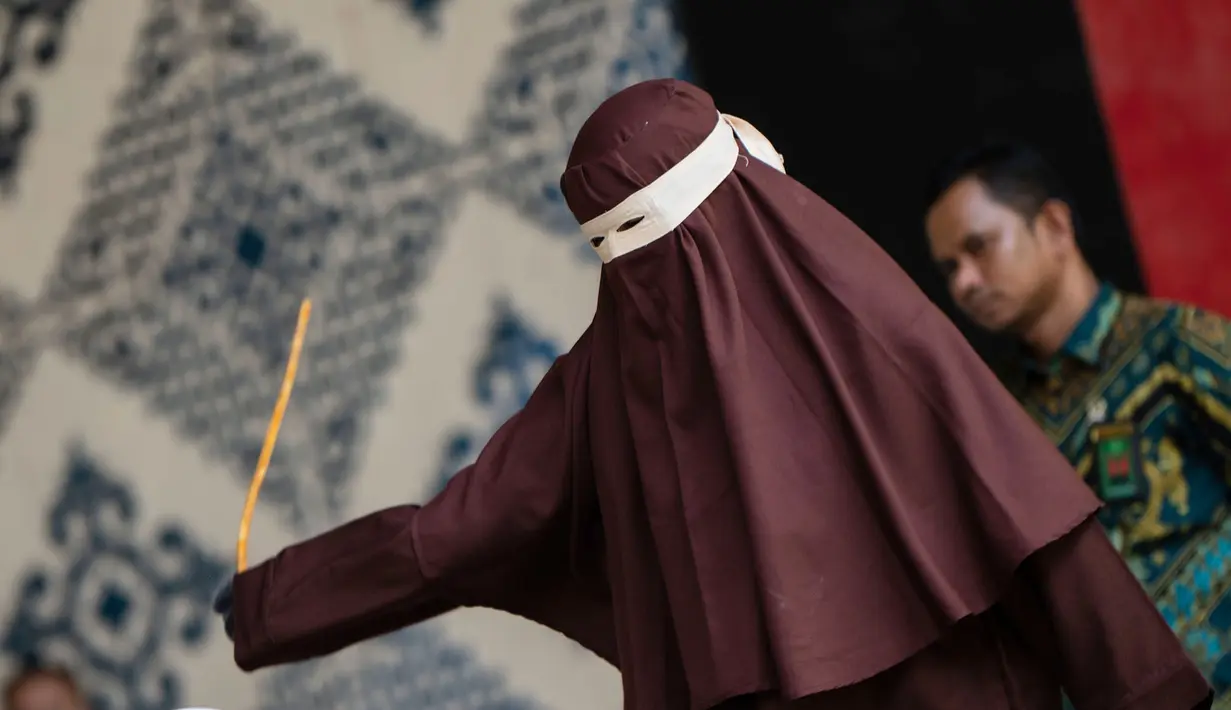 algojo mengeksekusi cambuk terhadap terpidana pelanggar hukum syariat Islam, diantaranya karena mencium seorang wanita saat siaran langsung TikTok, menjalani hukuman cambuk di Taman Bustanussalatin, Banda Aceh, Aceh, Kamis (2/7/2026). (AP Photo/Reza Saifullah)