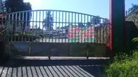 Gerbang Asrama Haji Tuminting Manado yang digembok serta dipasang spanduk penolakan.