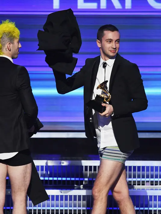 Personel Twenty One Pilots memperlihatkan celana panjangnya yang dilepas sesaat sebelum naik panggung menerima penghargaan Best Pop Duo/Group Performance pada ajang Grammy Awards 2017, Los Angeles, Minggu (12/2). (Kevin Winter/Getty Images for NARAS/AFP)