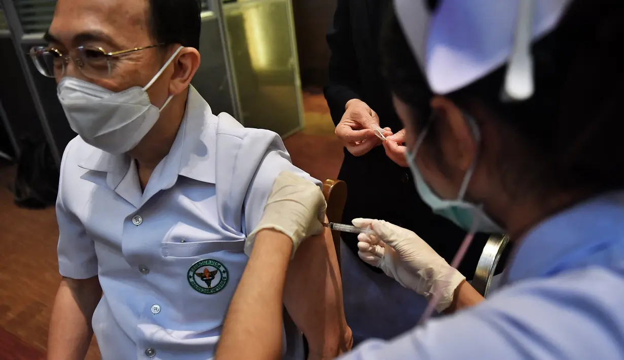 Seorang petugas kesehatan menerima vaksin Covid-19 CoronaVac dari Sinovac, di Institut Penyakit Menular Bamrasnaradura di Bangkok, Minggu (28/2/2021). Meski tertinggal diantara negara-negara Asia Tenggara lainnya, akhirnya Thailand memulai kampanye vaksin COVID-19. (Lillian SUWANRUMPHA/AFP)