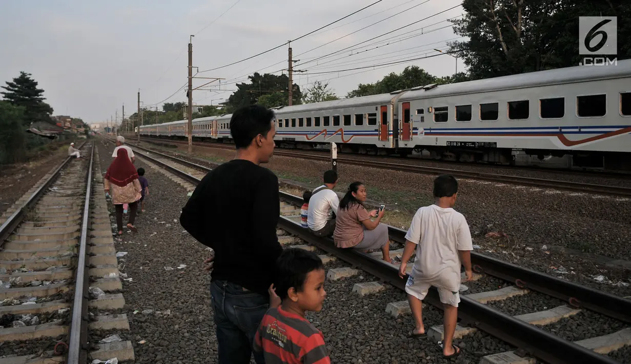 Anak-anak didampingi orang tuanya melihat kereta yang melintas saat menunggu waktu berbuka puasa atau ngabuburit di rel kereta Double Double Track (DDT) di Jakarta, Senin (21/5). (Merdeka.com/Iqbal S Nugroho)