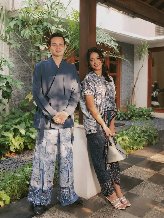 Amanda Khairunissa kenakan atasan kaftan dengan kain Batik bernuansa biru navy. Sang suami kenakan wrapped top polos dengan loose pants batik berwarna senada [@akhairunnisa]