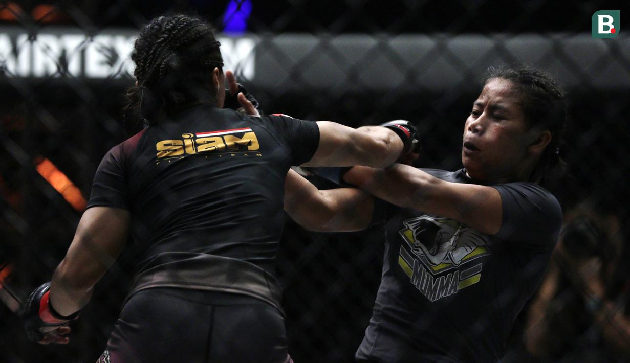 Petarung Indonesia, Priscilla Lumban Gaol, beradu pukulan dengan petarung Filipina, Angelie Sabanal, pada laga One Championship di Istora Senayan, Jakarta, Sabtu (17/11). Priscilla meraih kemenangan angka di kelas atomweight. (Bola.com/Yoppy Renato)