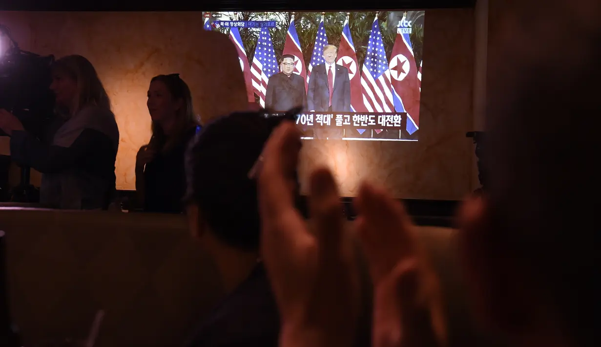 Orang-orang bertepuk tangan menonton pertemuan antara pemimpin Korea Utara Kim Jong-un dan Presiden AS Donald Trump di Koreatown, Los Angeles, Selasa (12/6). Untuk pertama kalinya dalam sejarah, Donald Trump dan Kim Jong-un bertemu. (AFP PHOTO/Robyn Beck)
