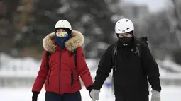Orang-orang memakai masker berjalan di sepanjang Rideau Canal Skateway pada hari pembukaannya di tengah pandemi COVID-19 di Ottawa, Ontario, Kamis (28/1/2021). Rideau Canal Skateway dibuka Kamis pagi dengan sejumlah tindakan pencegahan COVID-19. (Justin Tang/The Canadian Press via AP)