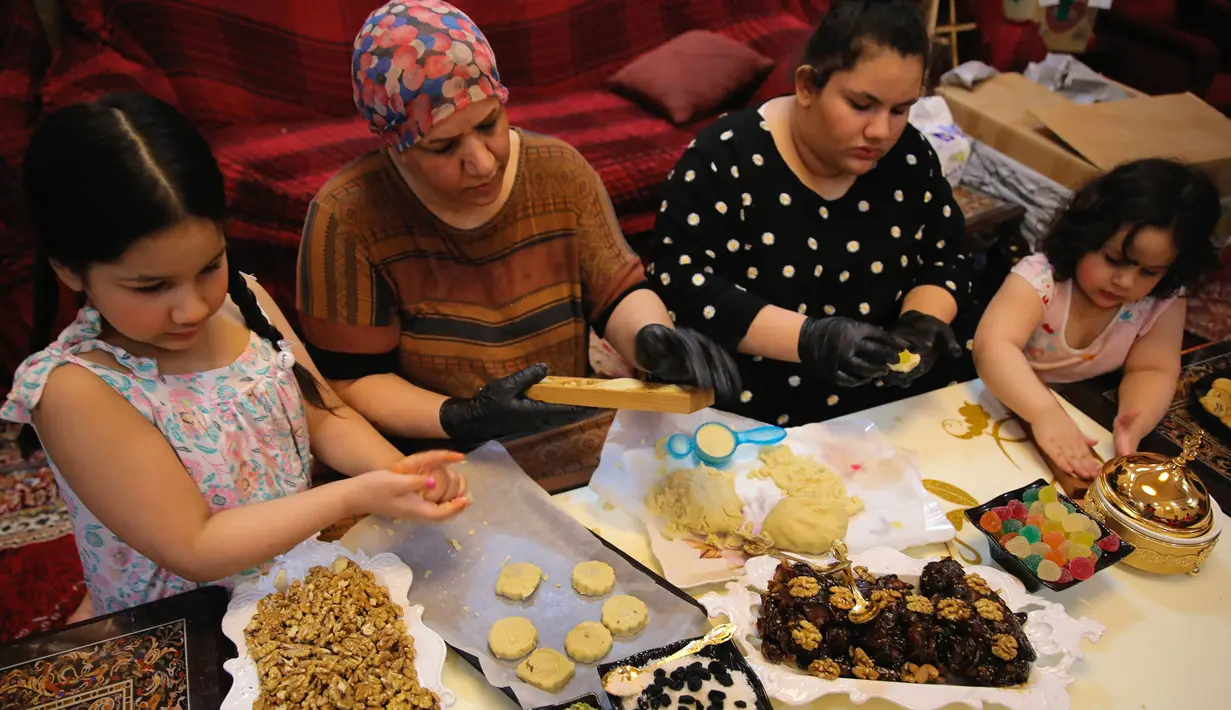 Sebuah keluarga menyiapkan kue pada hari pertama libur Idul Fitri di Basra, Irak, Kamis (13/5/2021). Umat muslim seluruh dunia merayakan Hari Raya Idul Fitri yang sekaligus menandai berakhirnya bulan suci Ramadhan. (AP Photo/Nabil al-Jurani)