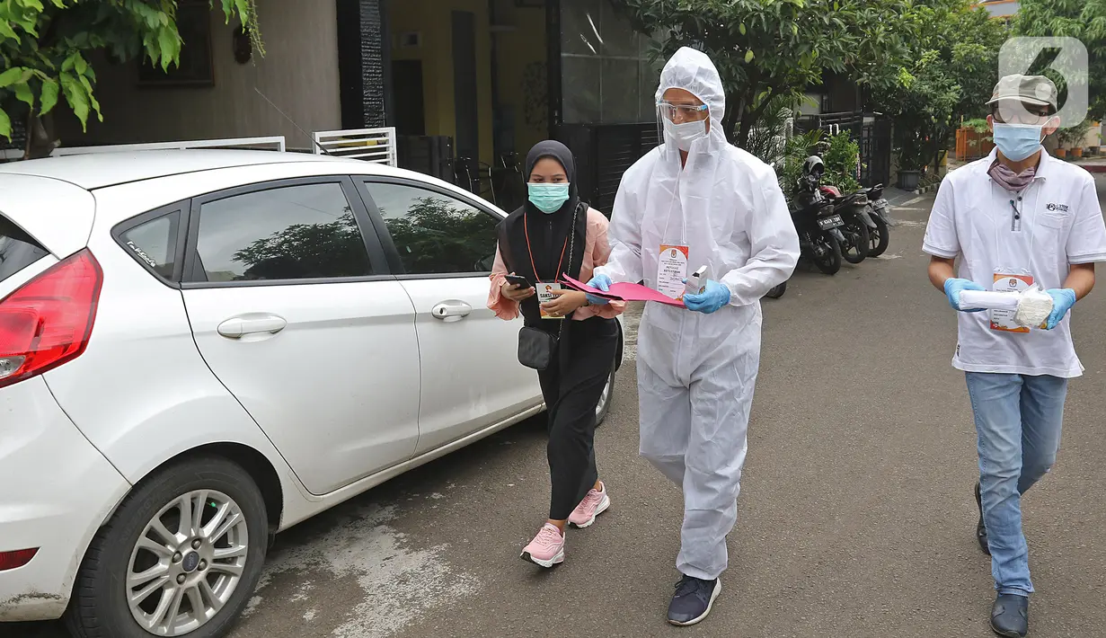 Petugas KPPS menggunakan hazmat sebelum menuju rumah pemilih di kawasan Depok, Rabu (9/12/2020). Petugas jemput bola atau mengambil suara dari warga yang diduga terpapar COVID-19 atau sedang menjalani isolasi mandiri di salah satu perumahan dalam Pilkada Depok 2020. (Liputan6.com/Herman Zakharia)