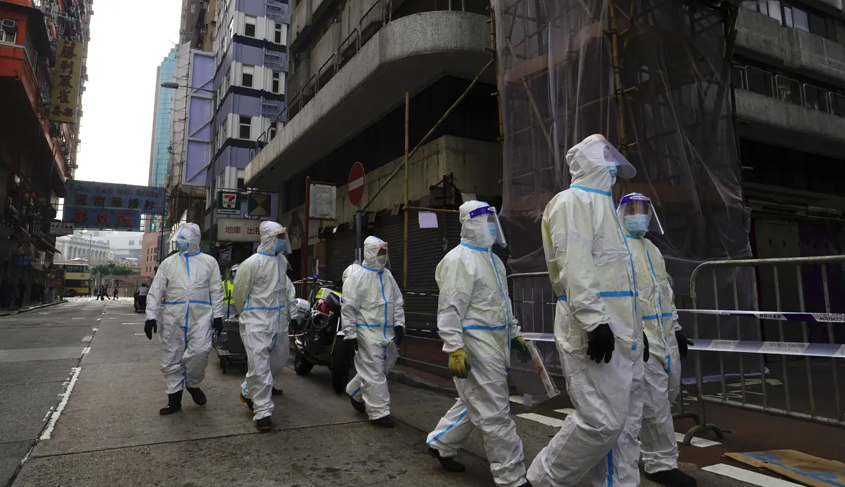Petugas kebersihan yang mengenakan pakaian pelindung berkumpul di daerah Yau Ma Tei, di Hong Kong, Sabtu (23/1/2021). Penguncian akan berlangsung sampai semua orang di area yang ditentukan telah diuji. (AP Photo/Vincent Yu)