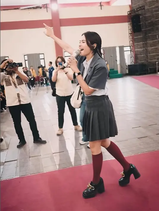 Setelan busana seragam SMA itu ditutup dengan kaus kaki panjang merah dan loafers heels hitam. [@maudyayunda]