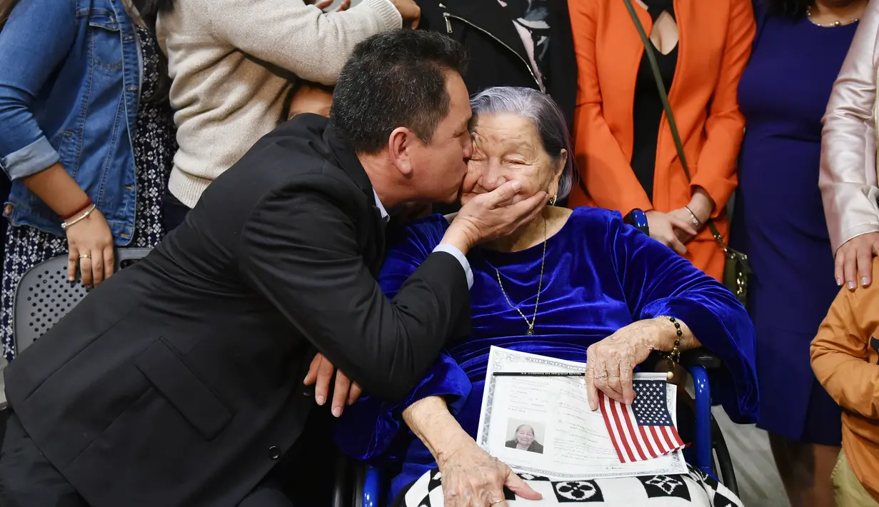 Ramon Bonilla mencium Maria Valles Bonilla (106) setelah sang nenek menjadi warga negara Amerika Serikat dalam upacara naturalisasi di kantor Citizenship and Immigration Services AS di Fairfax, Virginia, 6 November 2018. (MANDEL NGAN/AFP)
