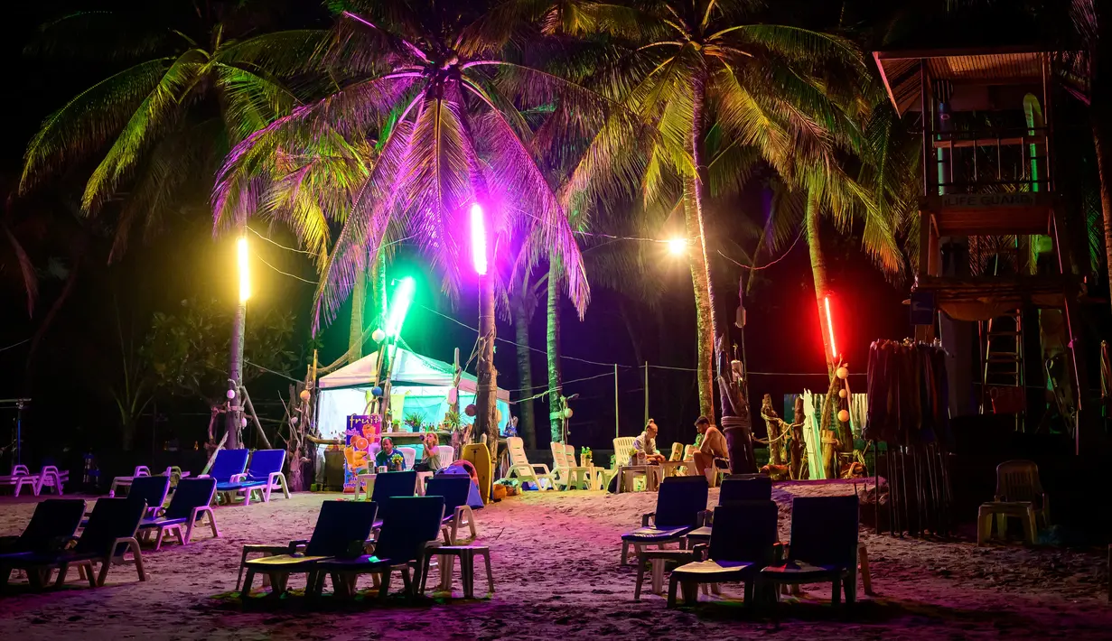 Orang-orang duduk di sebuah bar, saat para turis memanfaatkan program "Kotak Pasir Phuket" untuk pengunjung yang divaksinasi penuh terhadap virus corona Covid-19 di pulau Phuket Thailand (25/10/2021). (AFP/Mladen Antonov)