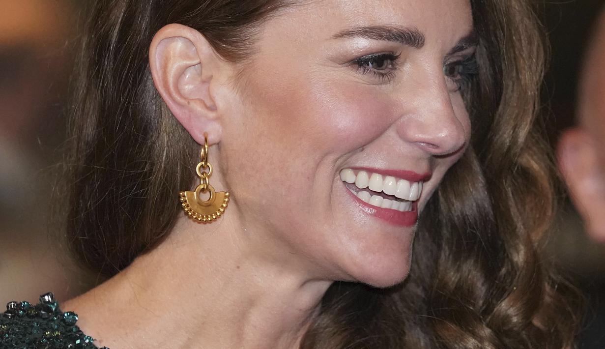 Kate Middleton, Duchess of Cambridge tersenyum selama Royal Variety Performance di Royal Albert Hall, London (18/11/2021). Kate menata rambutnya dengan ikal glamor yang jatuh ke satu sisi, meningkatkan penampilannya dengan anting-anting emas dan clutch hitam. (AFP/Justin Tallis)