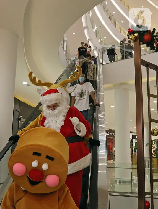 Petugas yang mengenakan kostum Sinterklas menaiki eskalator saat berkeliling menghibur pengunjung di Senayan City Mall, Jakarta, Jumat (25/12/2020). Pengunjung bisa berswafoto dan menikmati momen Natal bersama keluarga dan orang terkasih dengan "Santa and Friend". (Liputan6.com/Herman Zakharia)