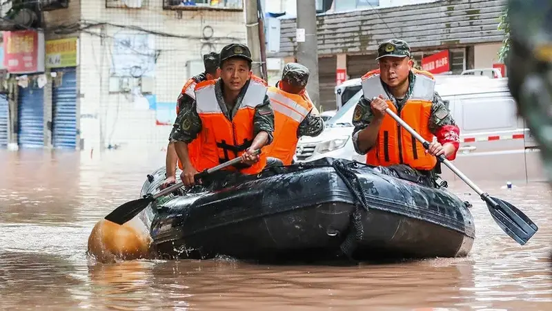 Polisi paramiliter menyieir daerah yang banjir oleh hujan lebat di Chongqing barat daya China. (AFP)