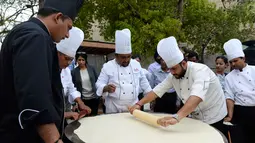 Koki India meratakan adonan saat membuat roti goreng Bhatura, India, New Delhi, Kamis (6/4). Penyelenggara berharap Bhatura buatan mereka bisa memecahkan rekor Bhatura  terbesar di India. (AFP PHOTO / SAJJAD HUSSAIN)