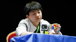 Seorang peserta memerhatikan rubiknya saat mengikuti kejuaraan kubus Rubik Dunia di Saint Denis, Paris, Prancis (16/7). (AFP Photo/Geoffroy Van Der Hasselt)