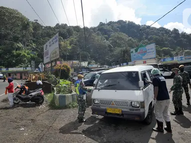 Petugas memeriksa kendaraan saat penyekatan arus lalu lintas di kawasan Ciloto, Cianjur, Jawa Barat, Jumat (17/4/2020). Pemkab Cianjur melakukan pengecekan suhu tubuh dan penyemprotan disinfektan di sejumlah titik keluar-masuk Cianjur untuk mencegah penyebaran COVID-19. (merdeka.com/Arie Basuki)