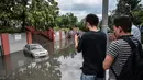 Seorang pria mengambil gambar sebuah mobil yang terendam akibat tingginya debit air banjir di kota Istanbul, Turki, Selasa (18/7). Sejumlah besar wilayah kota terendam banjir cukup parah akibat diguyur hujan lebat selama 12 jam. (OZAN KOSE / AFP)
