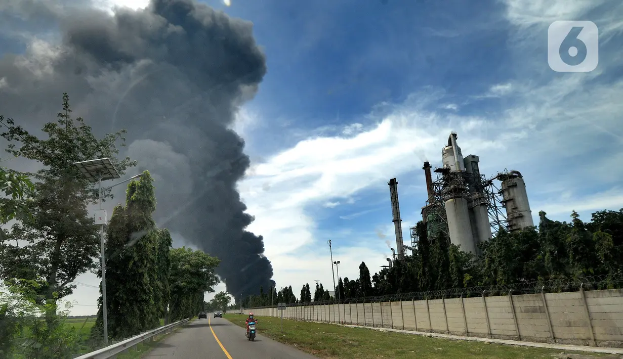 Kendaraan melintas dengan latar belakang kepulan asap akibat kebakaran Kilang Balongan di Indramayu, Jawa Barat, Senin (29/03/2021). Dampak dari terbakarnya kilang minyak Balongan milik PT Pertamina itu mengakibatkan Jalan Raya Balongan-Indramayu ditutup total. (merdeka.com/Arie Basuki)