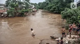 Seorang anak melompat ke Kali Ciliwung yang meluap, Kebon Pala, Jatinegara, Jakarta Timur, Minggu (31/10/2021). Aliran Kali Ciliwung yang meluap akibat hujan di kawasan hulu dimanfaatkan anak-anak untuk berenang meski membahayakan keselamatan. (merdeka.com/Iqbal S. Nugroho)