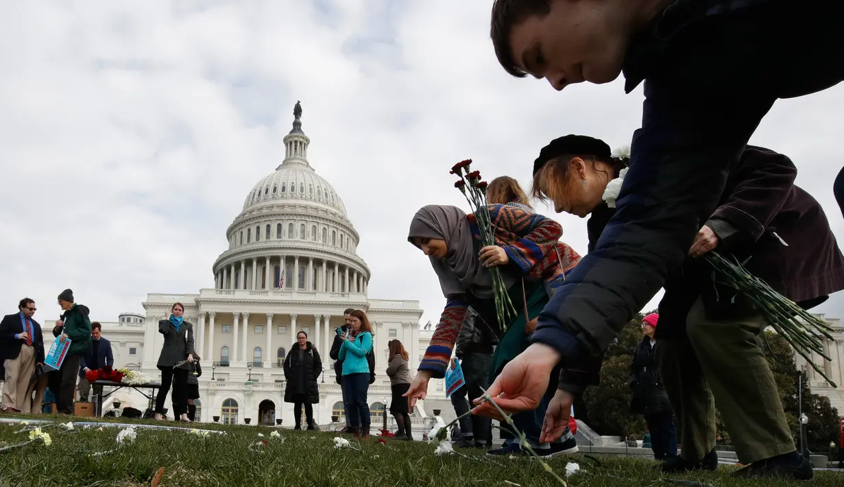 Sejumlah bunga diletakkan memenuhi halaman rumput Gedung Capitol (kantor kongres) Amerika Serikat, Senin (19/3). 5000 bunga diletakkan untuk mengenang ribuan anak yang tewas akibat pengeboman oleh koalisi pimpinan Arab Saudi di Yaman (AP/Jacquelyn Martin)
