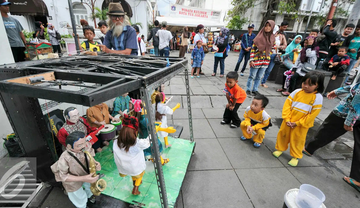 Pak Muchtar saat menghibur dengan boneka talinya di kawasan Kota Tua Jakarta, Kamis (17/12/2015). Pria berumur 70 itu dengan cekatan memainkan tuas penggerak yang membuat bonekanya bergoyang mengikuti irama dangdut. (Liputan6.com/Yoppy Renato)