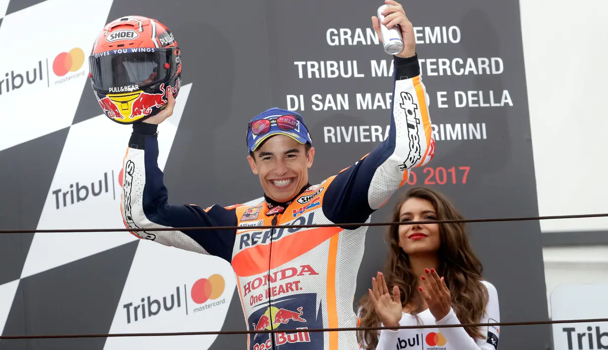 Pembalap Repsol Honda, Marc Marquez merayakan kemenangannya di atas podium MotoGP San Marino 2017 di Italia, Minggu (10/9). Kemenangan di Misano membuat Marquez kembali ke puncak klasemen sementara MotoGP 2017. (AP Photo/Antonio Calanni)