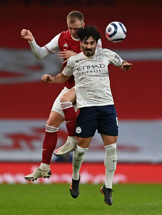 Gelandang Manchester City, Ilkay Gundogan (kanan) bersaing dengan bek Arsenal, Rob Holding pada lanjutan Liga Inggris di Emirates Stadium, Minggu (21/2/2021). Manchester City kian mengokohkan posisinya di puncak klasemen setelah menang 1-0 di kandang Arsenal.  (Shaun Botterill / POOL / AFP)