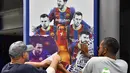 Pekerja melepas poster-poster yang menampilkan pemain depan Barcelona Lionel Messi di stadion Camp Nou di Barcelona (10/8/2021). Prancis menunggu dengan tidak sabar Lionel Messi dengan para pendukung berkumpul di luar lapangan Paris Saint-Germain. (AFP/ Pau Barrena)