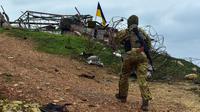 Bendera Ukraina terlihat dipasang di sebuah bangunan saat seorang tentara Ukraina berjalan di Pulau Ular, Laut Hitam, Ukraina, 18 Desember 2022. Pasukan Rusia menduduki pulau itu pada awal-awal invasinya ke Ukraina, namun akhirnya mundur beberapa bulan kemudian. (AP Photo/Michael Shtekel)