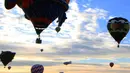 Sejumlah  balon udara melintas di atas nelayan selama Festival Balon Internasional XVIII di Leon, Meksiko pada 18 November 2018. Sekitar 200 balon udara dari 23 negara terbang di atas bendungan Palote. (Photo by MARIO ARMAS / AFP)