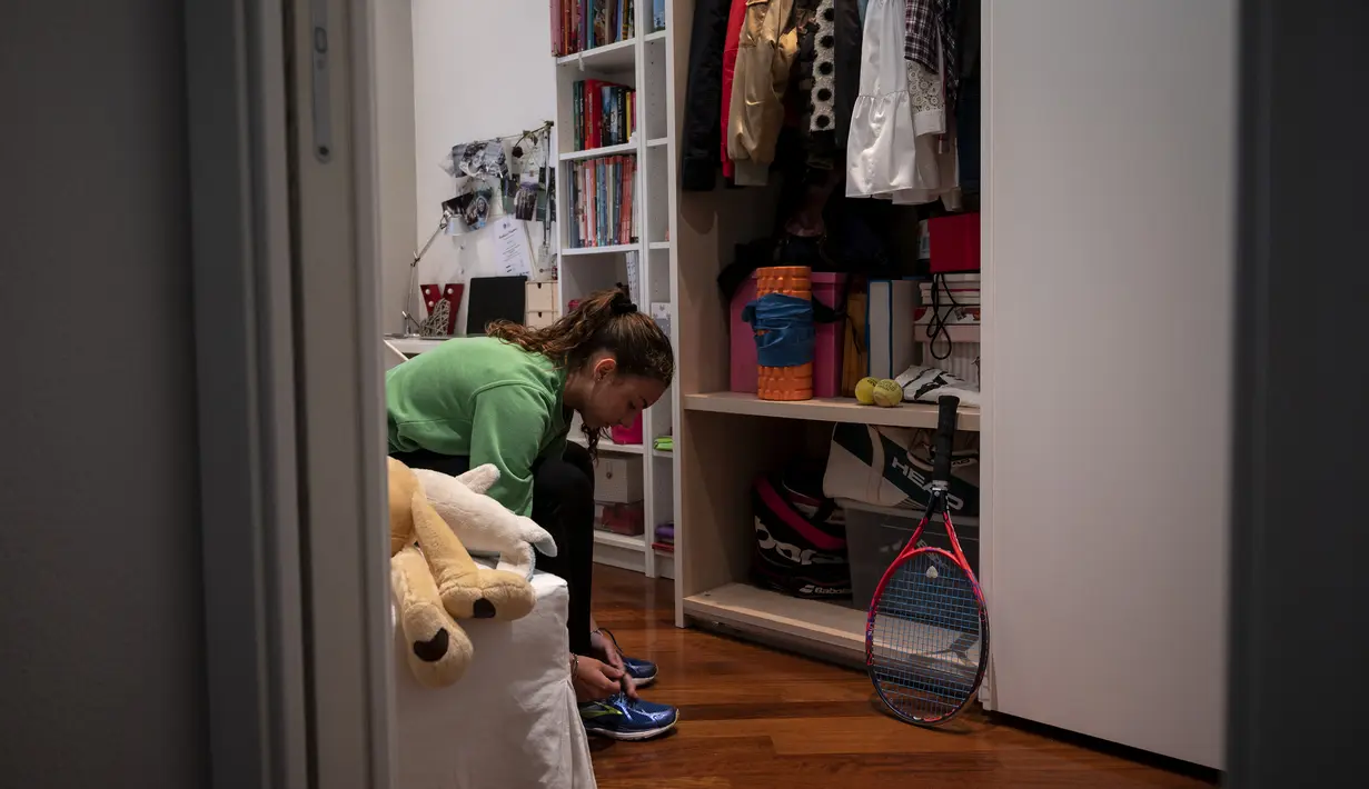 Vittoria Oliveri memakai sepatu sebelum bermain tenis dengan Carola Pessina di atap rumah mereka selama lockdown COVID-19 di Finale Ligure, Italia (19/4/2020). Setiap hari Carola, 11, dan Vittoria, 13, bermain tenis dari satu atap ke atap lain di rumah mereka untuk berlatih. (AFP/Marco Bertorello)