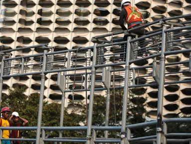 Pekerja menyelesaikan revitalisasi Jembatan Penyeberangan Orang (JPO) Gelora Bung Karno (GBK), Jakarta, Selasa (27/11). Pemprov DKI Jakarta merevitalisasi tiga JPO di Polda Metro Jaya, GBK dan Bundaran Senayan. (Liputan6.com/Faizal Fanani)