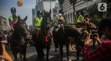 Sejumlah anak berfoto dengan polisi berkuda dari Direktorat Polisi Satwa Mabes Polri di kawasan Bundaran HI, Jakarta, Minggu (17/11/2019). Polisi berkuda tersebut khusus ditugaskan mengawasi keamanan CFD serta memperkenalkan kepada warga. (Liputan6.com/Faizal Fanani)