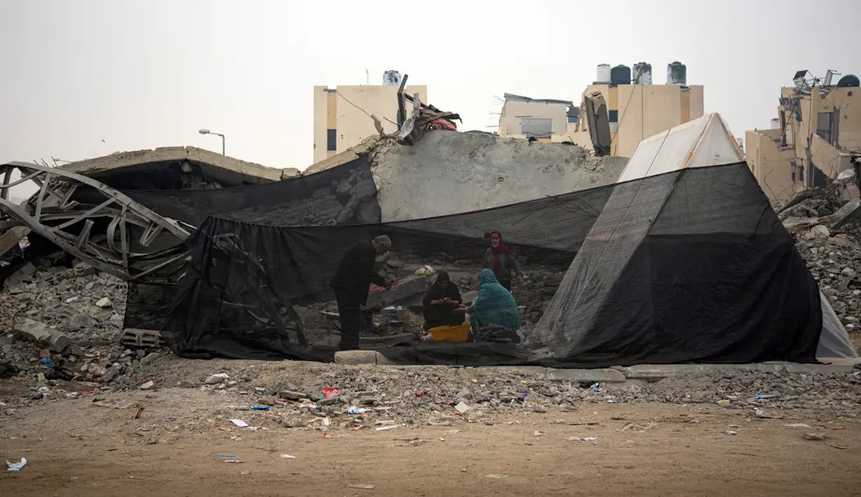 Warga Palestina yang mengungsi akibat bombardir Israel terhadap Jalur Gaza memasak di tenda kamp darurat di kawasan Muwasi, Kamis (28/12/2023). (AP Photo/Fatima Shbair)