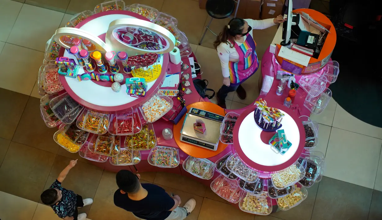 Seorang ayah dan anak membeli permen di sebuah toko di Abasto Shopping Mall di Buenos Aires, Argentina, Rabu (14/10/2020). Setelah tujuh bulan ditutup, pusat perbelanjaan Buenos Aires dibuka kembali saat lonjakan kasus COVID-19 terjadi di pedalaman negara itu. (AP Photo/Victor R. Caivano)