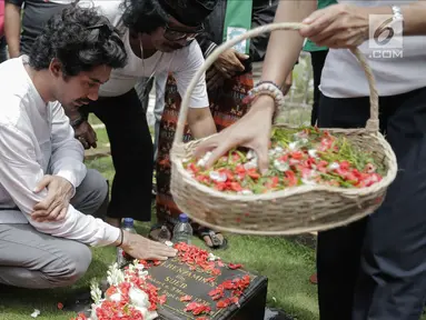 Aktor Reza Rahadian menaburkan bunga di makam Benyamin Sueb di Karet Bivak, Jakarta, Jumat (26/1). Ziarah tersebut ditemani anak ketiga almarhum, H. Beni dan para fans, Benyamin Sueb Fans Club. (Liputan6.com/Faizal Fanani)