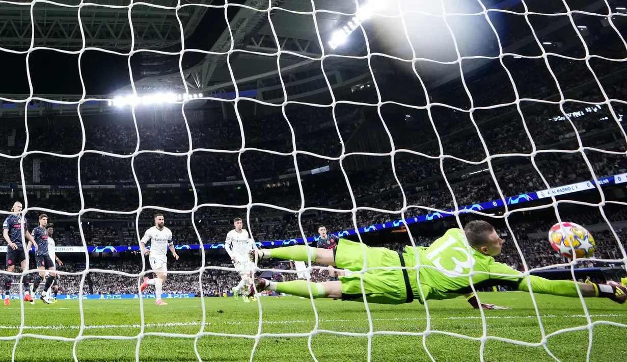 Kiper Real madrid, Andriy Lunin kebobolan gol pertama hasil bunuh diri Ruben Dias yang berusaha memblok tendangan bebas gelandang Manchester City, Bernardo Silva pada laga leg pertama babak perempatfinal Liga Champions 2023/2024 di Santiago Bernabeu Stadium, Selasa (9/4/2024) malam. (AP Photo/Manu Fernandez)