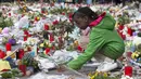 Seorang anak kecil meletakkan bunga di sebuah tugu peringatan saat aksi pawai menentang teror dan kebencian di Brussels, ibu kota Belgia, Minggu (17/4). Dalam aksi ini, banyak peserta membawa bunga dan lambang-lambang perdamaian. (REUTERS/Yves Herman)