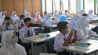 Siswa mengikuti kegiatan belajar mengajar pada hari pertama pembelajaran tatap muka di SMP 26 Depok, Depok, Jawa Barat, Senin (24/1/2022). Pemerintah Kota Depok mulai menggelar Pembelajaran Tatap Muka (PTM) secara penuh atau 100 persen mulai hari ini. (Liputan6.com/Herman Zakharia)