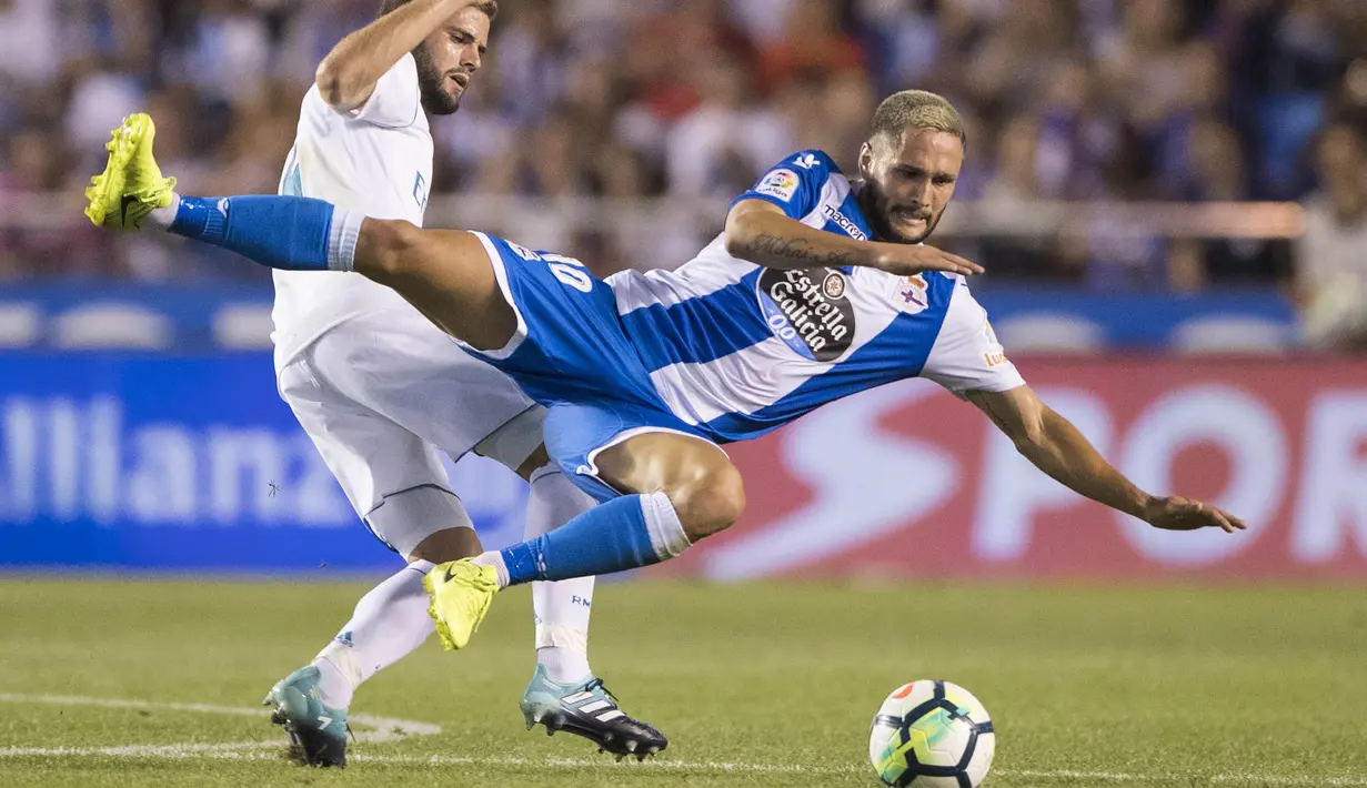 Striker Deportivo La Coruna, Florin Andone, terjatuh saat berebut bola dengan bek Real Madrid, Nacho, pada laga La Liga di Stadion Riazor, Senin (21/8/2017). Real Madrid menang 3-0 atas Deportivo La Coruna. (AP/Lalo R. Villar)