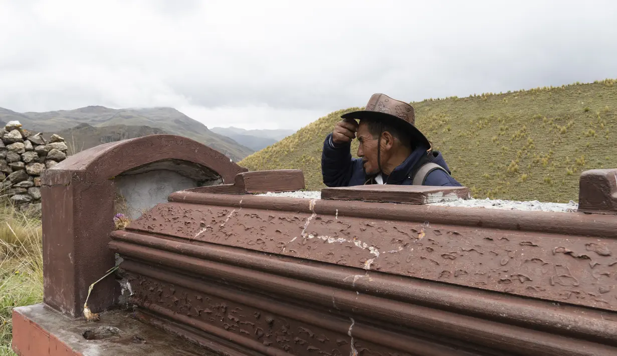 Gembala alpaka Esteban Taipe memeriksa sebuah makam di pemakaman kota hantu Santa Barbara, Peru, Sabtu (4/12/2021). Taipe telah menjadi pemandu wisata tidak resmi kota yang memiliki hampir 200 bangunan terbengkalai. (AP Photo/Franklin Briceño)