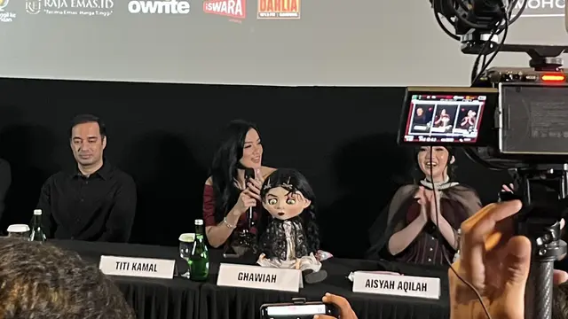 Titi Kamal, memegang mic dalam konferensi pers dan screening film "The Doll Ghawiah" di kawasan Jakarta pada (16/10/2026)/ (Liputan6.com/Afradhiya N. R)