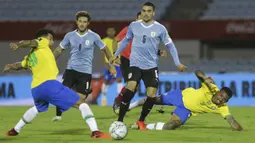 Penyerang Brasil, Roberto Firmino, berebut bola dengan gelandang Uruguay, Nahitan Nandez, pada laga lanjutan kualifikasi Piala Dunia zona CONMEBOL di Estadio Centenario, Rabu (18/11/2020) pagi WIB. Brasil menang 2-0 atas Uruguay. (AFP/Matilde Campodonico/pool)